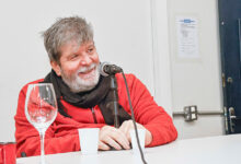 Homem diante de um microfone, sorrindo.