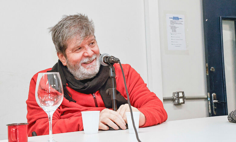 Homem diante de um microfone, sorrindo.