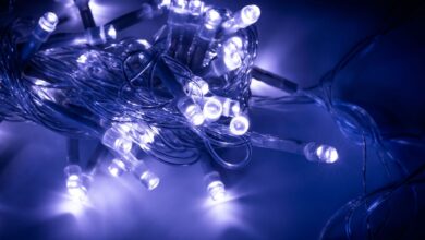 Cordão de luzes LED azuis e brancas emaranhado sobre superfície escura, demonstrando a versatilidade decorativa dos diodos emissores de luz