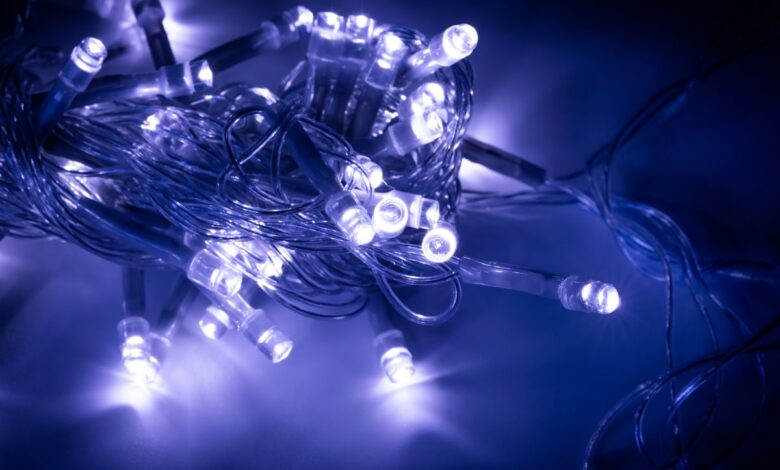 Cordão de luzes LED azuis e brancas emaranhado sobre superfície escura, demonstrando a versatilidade decorativa dos diodos emissores de luz