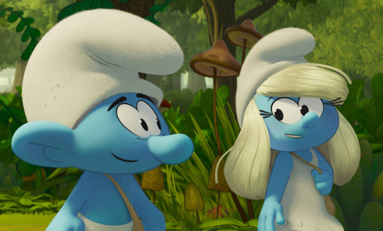 A imagem mostra dois Smurfs em um ambiente de floresta. Um Smurf tem pele azul e usa um chapéu branco, enquanto a Smurfete também tem pele azul e cabelo loiro, usando um vestido branco. Ao fundo, há vegetação densa e árvores, criando um cenário natural.