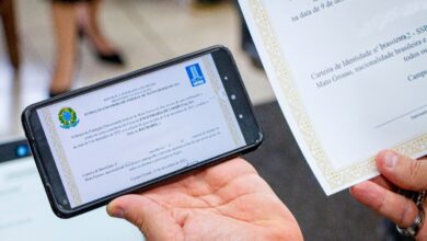 Pessoa exibindo diploma digital de graduação em smartphone e versão impressa