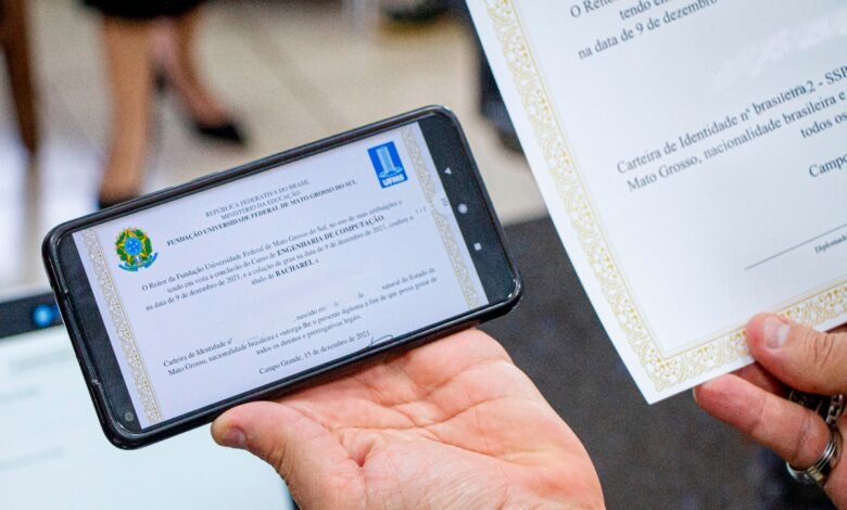 Pessoa exibindo diploma digital de graduação em smartphone e versão impressa