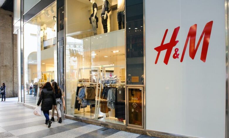 Fachada iluminada da H&M em shopping brasileiro com clientes entrando.