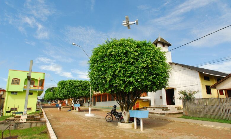 Vista urbana de Marechal Thaumaturgo com avião sobrevoando a cidade, mostrando o isolamento e o acesso aéreo típico da região amazônica.