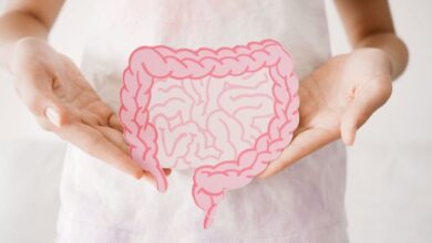 Imagem de uma pessoa com camiseta branca e com as mãos segurando a ilustração de um intestino humano