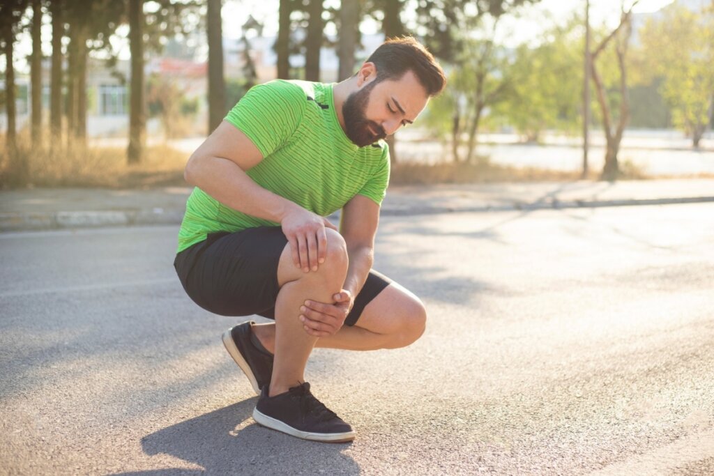 A falta de movimentação regular pode favorecer a rigidez muscular e reduzir a flexibilidade ao longo do tempo Homem em um parque inclinado olhando o seu joelho